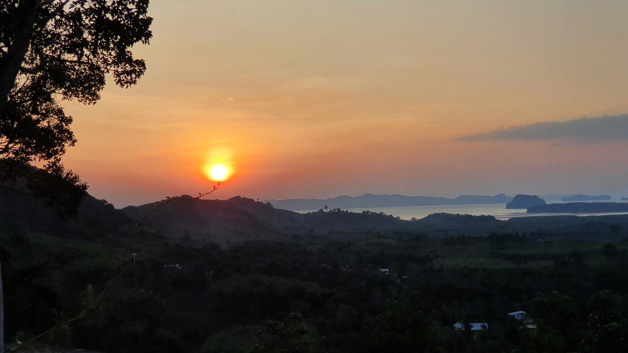 journeyjoy.org Krabi Travel Guide: Sunset at Din Daeng Doi Viewpoint with the sky glowing in shades of amber and coral above lush mangroves and distant limestone hills.